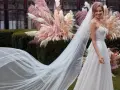 La sposa sorride, il suo abito bianco e il velo fluttuano dolcemente tra le pampas rosa.