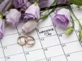 Anelli d'oro su un calendario segnato con "Wedding" e fiori lilla. Il giorno perfetto quando sposarsi.