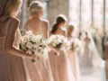 Damigelle d'onore in abiti rosa cipria, ognuna con un bouquet di rose bianche. Quante damigelle si possono avere per un matrimonio da sogno?