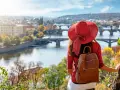 Donna con cappello rosso ammira Praga in autunno. Il periodo migliore per andare a Praga è quando la natura si tinge di colori caldi.