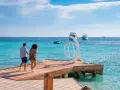 Coppia passeggia su un molo di legno a **Orgada Egitto**, con acque turchesi e barche all'orizzonte.