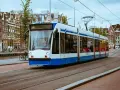 Un tram bianco e blu sferraglia sui binari, un modo efficiente per capire come muoversi ad Amsterdam tra case storiche e canali.
