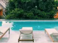 Piscina con lettini e vegetazione lussureggiante, un'oasi perfetta per sapere dove dormire a Bangkok.