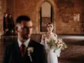 La sposa, con un bouquet rustico, attende il suo sposo in un'antica sala. Un venerdì speciale per sposarsi.