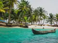 Barca in un mare turchese, palme e spiaggia. Un'idea perfetta per sapere dove andare al mare a Capodanno.