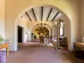 Interno accogliente con archi in pietra, un murale di un albero antico e arredi che evocano l'atmosfera dell'antico borgo di Sutri.