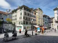 Piazza di Zurigo con edifici colorati, negozi e persone che passeggiano. Ideale per scoprire cosa vedere a Zurigo in un giorno.