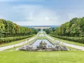 Giardini maestosi con fontane barocche e un palazzo imponente in lontananza, ricordano i fasti dei mulini reali.