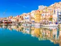 Porto di Sciacca, cosa vedere: barche da pesca ormeggiate e case colorate che si specchiano sull'acqua cristallina.