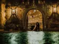 Una coppia di sposi si abbraccia sotto un arco del castello di San Basilio, illuminato da lanterne e luci soffuse. L'acqua riflette l'atmosfera magica.
