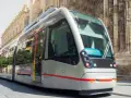 Tram moderno sfreccia davanti alla cattedrale, un modo efficiente per capire come muoversi a Siviglia.