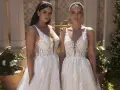 Due modelle con abiti da sposa in pizzo, con diversi tipi di scollatura a V e dettagli floreali, posano all'aperto.