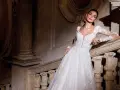 Modella con abiti da sposa per sembrare più alte, posa su una scala di pietra antica.