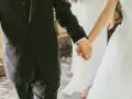 Mani intrecciate, un uomo in abito scuro e una sposa in bianco. Il vero significato di sposa è l'amore che unisce.