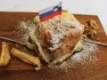 Una fetta di torta con bandierina slovena, noci e mele essiccate, un assaggio dei piatti tipici sloveni.