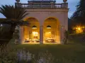 Villa Carrara a Genova, con portico illuminato e giardino serale.