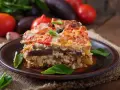 Un assaggio di cosa mangiare a Santorini: una saporita moussaka con melanzane, pomodori e formaggio, guarnita con basilico fresco.