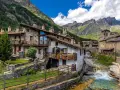 Un incantevole borgo da visitare in Piemonte, con case in pietra, balconi fioriti e un torrente che scorre tra le montagne.