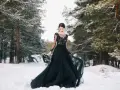 Una sposa in un bosco innevato indossa un abito da sposa nero, un simbolo di audacia e individualità.