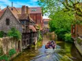 Giro in barca sui canali di Bruges, un'ottima idea per cosa vedere a Bruges in un giorno, tra case storiche e vegetazione lussureggiante.