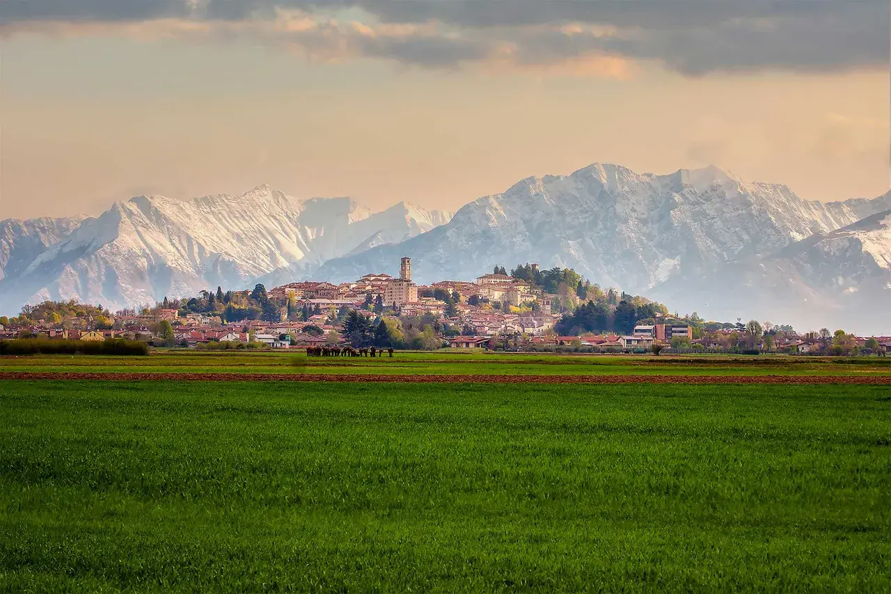 Campi verdi e montagne innevate incorniciano il borgo di San Daniele.