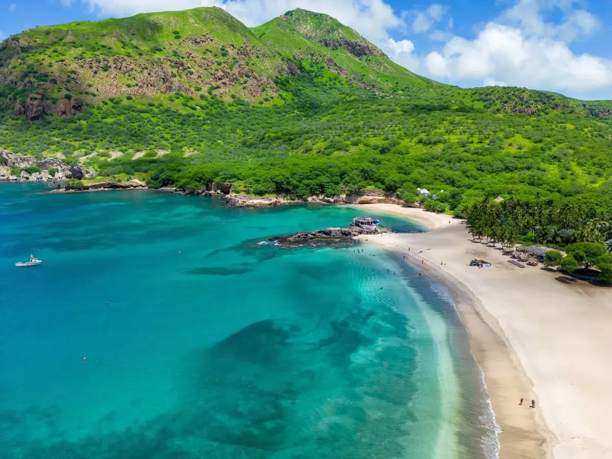 Spiaggia tropicale con mare turchese e montagne verdi. Un vero capo verde, ideale per una vacanza da sogno.