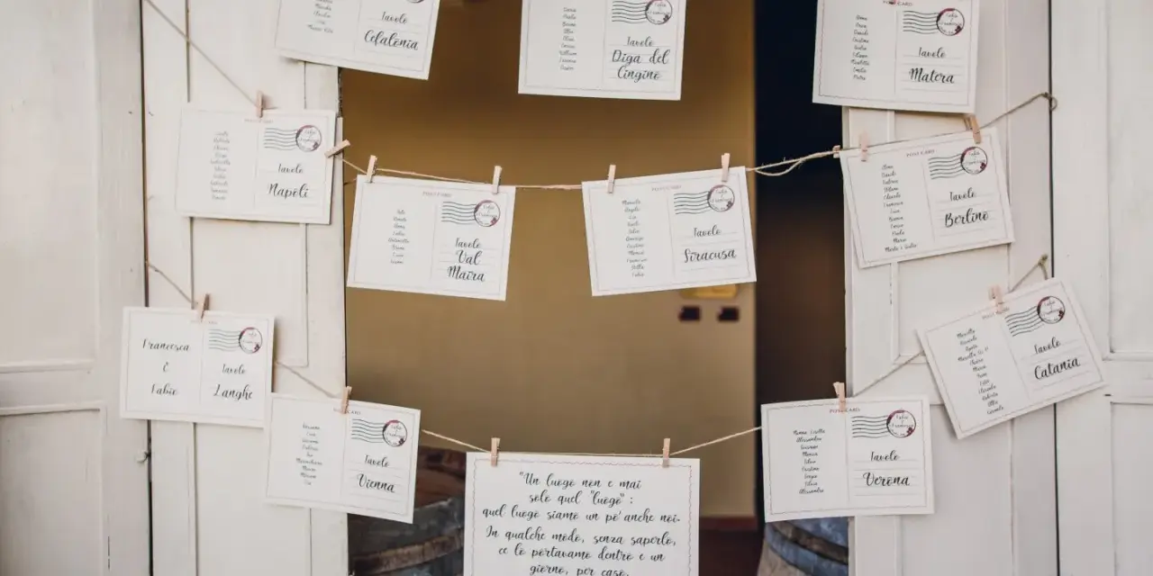 Tableau mariage idee: cartoline con nomi degli invitati e destinazioni, appese a filo con mollette.