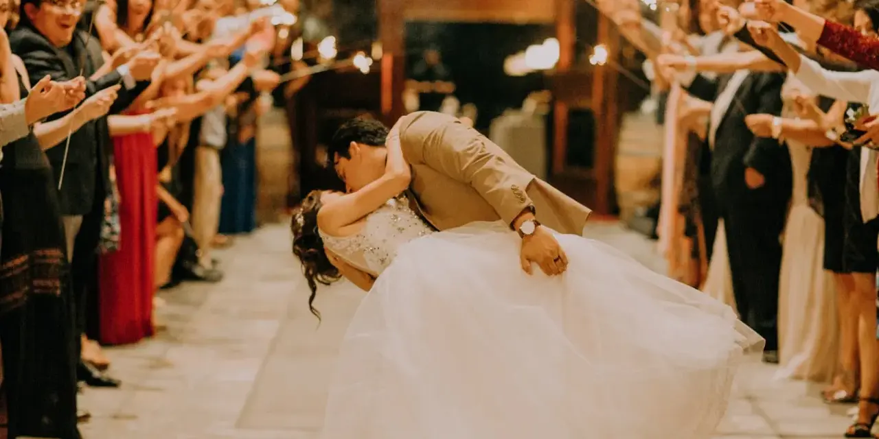 La sposa e lo sposo si baciano tra le scintille dei bengala, circondati da amici e parenti festanti. Un momento magico che sembra uscito da un gioco.