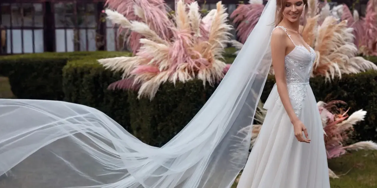 La sposa sorride, il suo abito bianco e il velo fluttuano dolcemente tra le pampas rosa.
