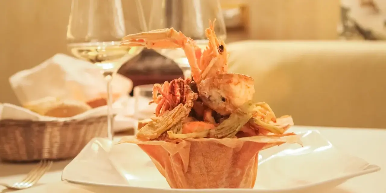 Frittura di pesce croccante, un'ottima idea per dove mangiare a Padova spendendo poco. Accompagnata da vino bianco e pane fresco.