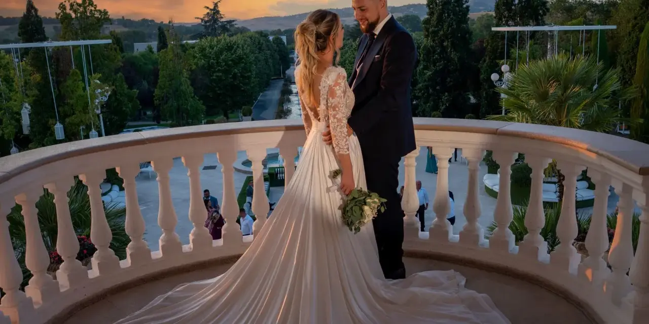 Coppia felice sul balcone al tramonto, con un abito da sposa da favola. Il loro fidanzamento ufficiale è celebrato in un'atmosfera magica.