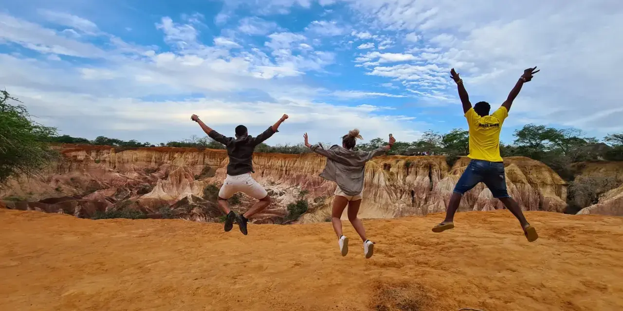 Tre amici saltano felici in Kenya, un'esperienza indimenticabile che vale ogni euro del costo safari Kenya.
