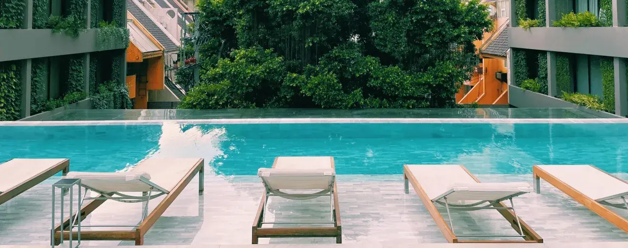 Piscina con lettini e vegetazione lussureggiante, un'oasi perfetta per sapere dove dormire a Bangkok.
