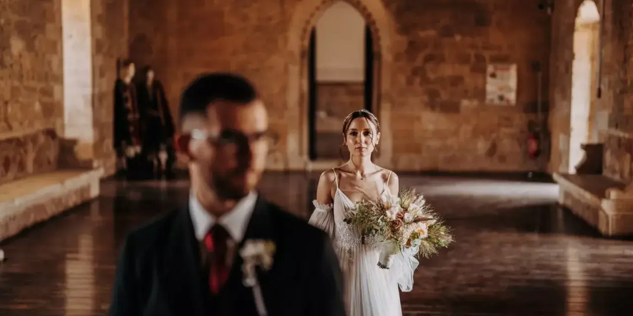 La sposa, con un bouquet rustico, attende il suo sposo in un'antica sala. Un venerdì speciale per sposarsi.