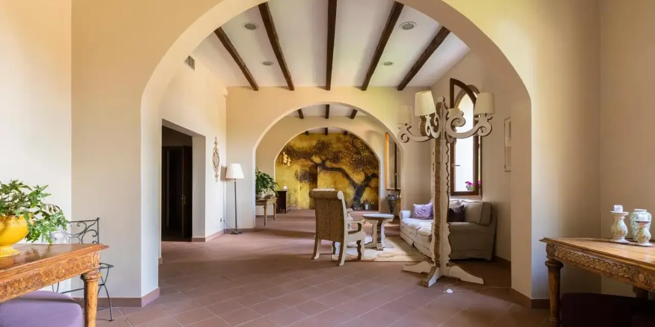 Interno accogliente con archi in pietra, un murale di un albero antico e arredi che evocano l'atmosfera dell'antico borgo di Sutri.