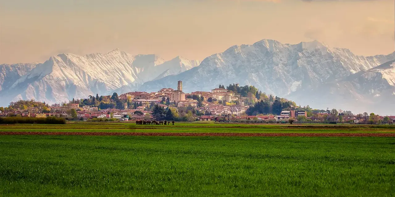 Campi verdi e montagne innevate incorniciano il borgo di San Daniele.