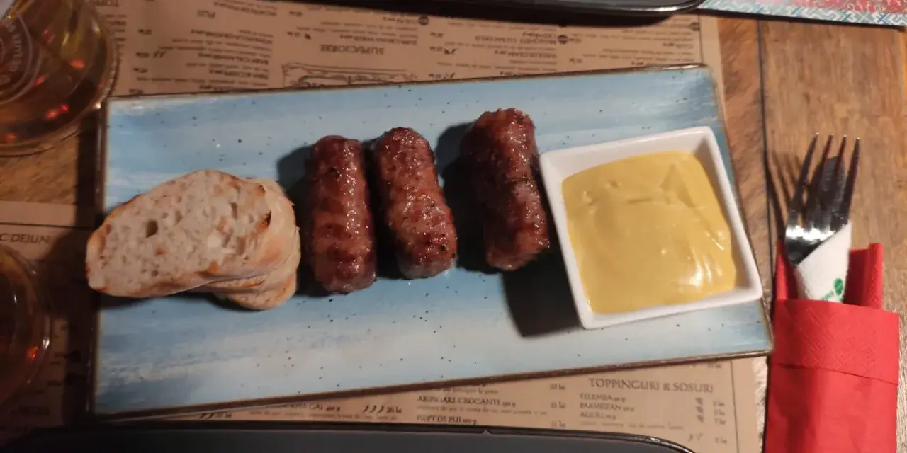 Mici e pane: un assaggio di cosa mangiare a Bucarest. Salsicce grigliate servite con pane fresco e senape.