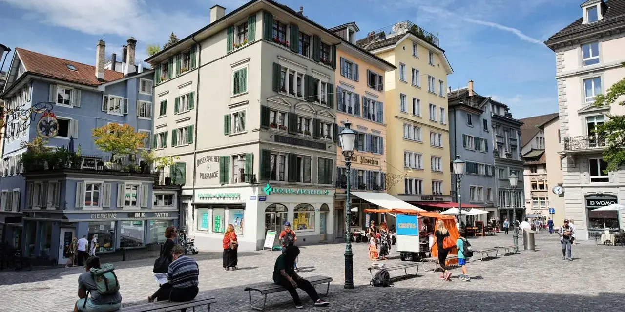 Piazza di Zurigo con edifici colorati, negozi e persone che passeggiano. Ideale per scoprire cosa vedere a Zurigo in un giorno.