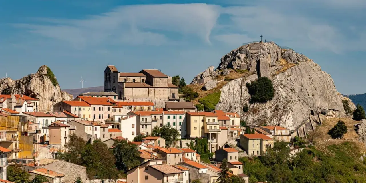 Borgo arroccato con case dai tetti rossi, una chiesa imponente e una roccia con croce in cima. Un luogo da scoprire tra le meraviglie di cosa vedere in Molise.