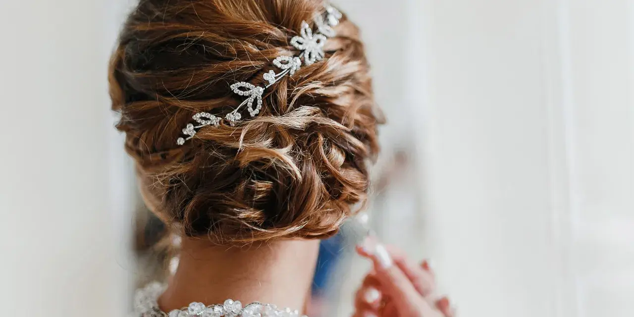Splendida acconciatura alta sposa con fermaglio scintillante e collana di perle.