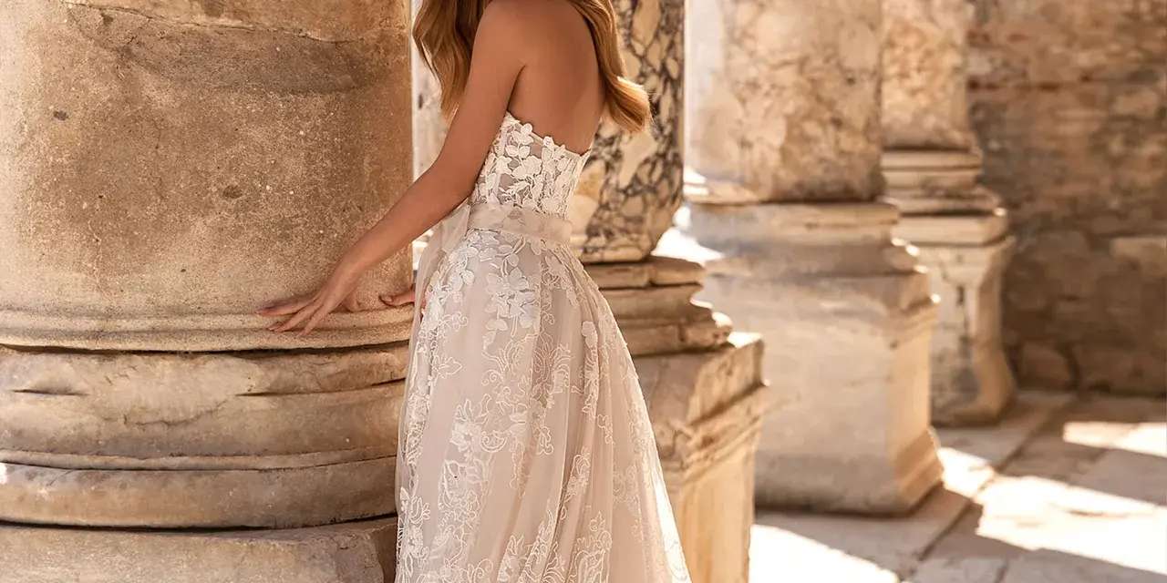 Modella con un abito da sposa in pizzo, tra colonne antiche. Il costo abito da sposa è un investimento per un sogno.