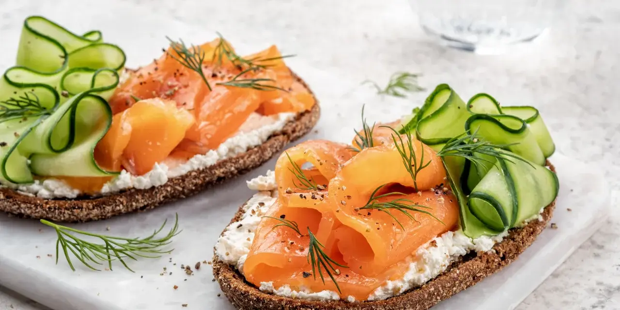 Smørrebrød con salmone affumicato, cetrioli e aneto. Un'idea su cosa mangiare a Copenaghen per un pranzo leggero e gustoso.