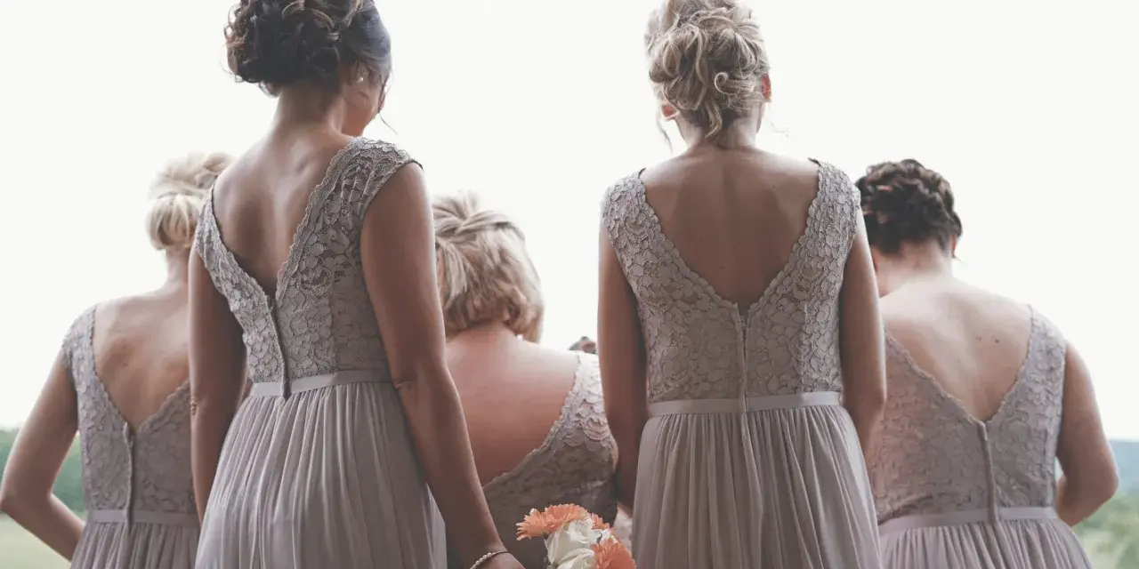 Cinque donne con abiti da damigella, una tiene un bouquet. Si percepisce la differenza tra damigella e testimone.