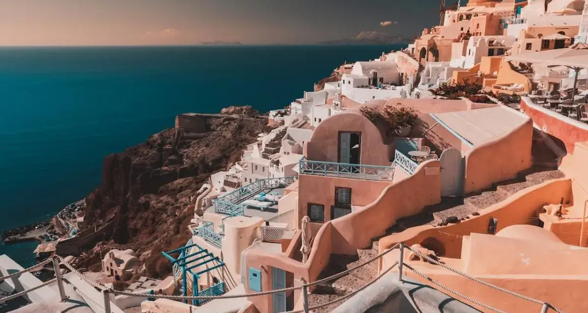 Case bianche e blu aggrappate alla scogliera di Santorini, un sogno per chi cerca cosa fare a Santorini in 7 giorni.