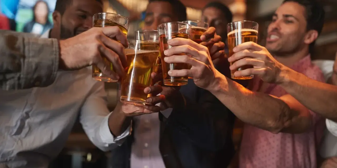 Amici brindano con birra in un locale, un brindisi per l'addio al celibato.