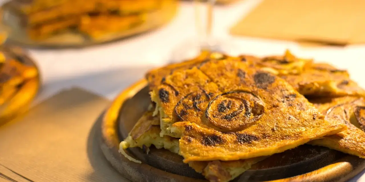 Farinata, una delizia da provare per scoprire cosa mangiare a Pisa. Croccante fuori e morbida dentro, con cipolle caramellate.