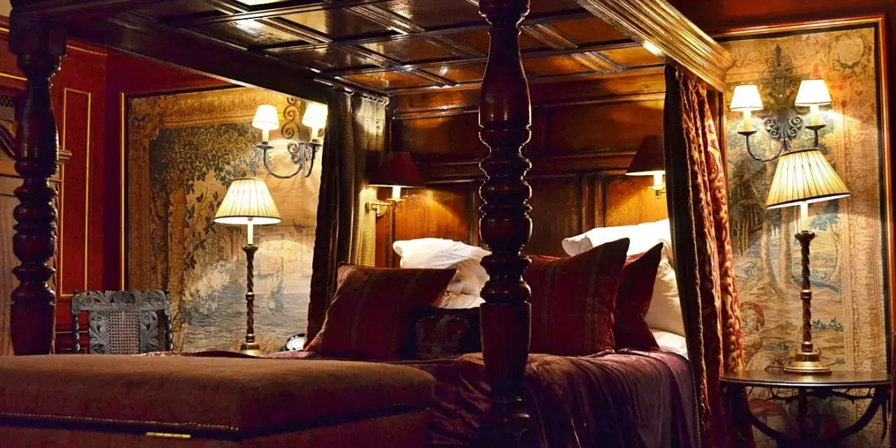 Lussuosa camera da letto con letto a baldacchino, arazzi storici e lampade eleganti. Un'idea di dove dormire a Edimburgo per un soggiorno da re.