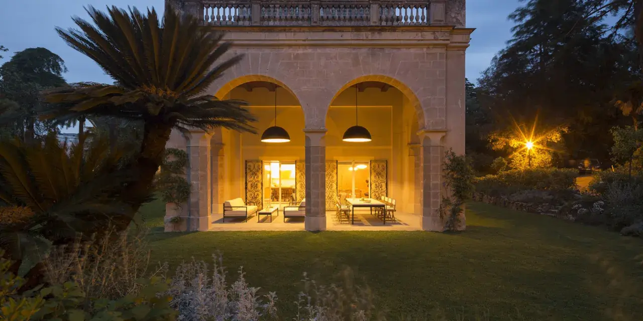 Villa Carrara a Genova, con portico illuminato e giardino serale.