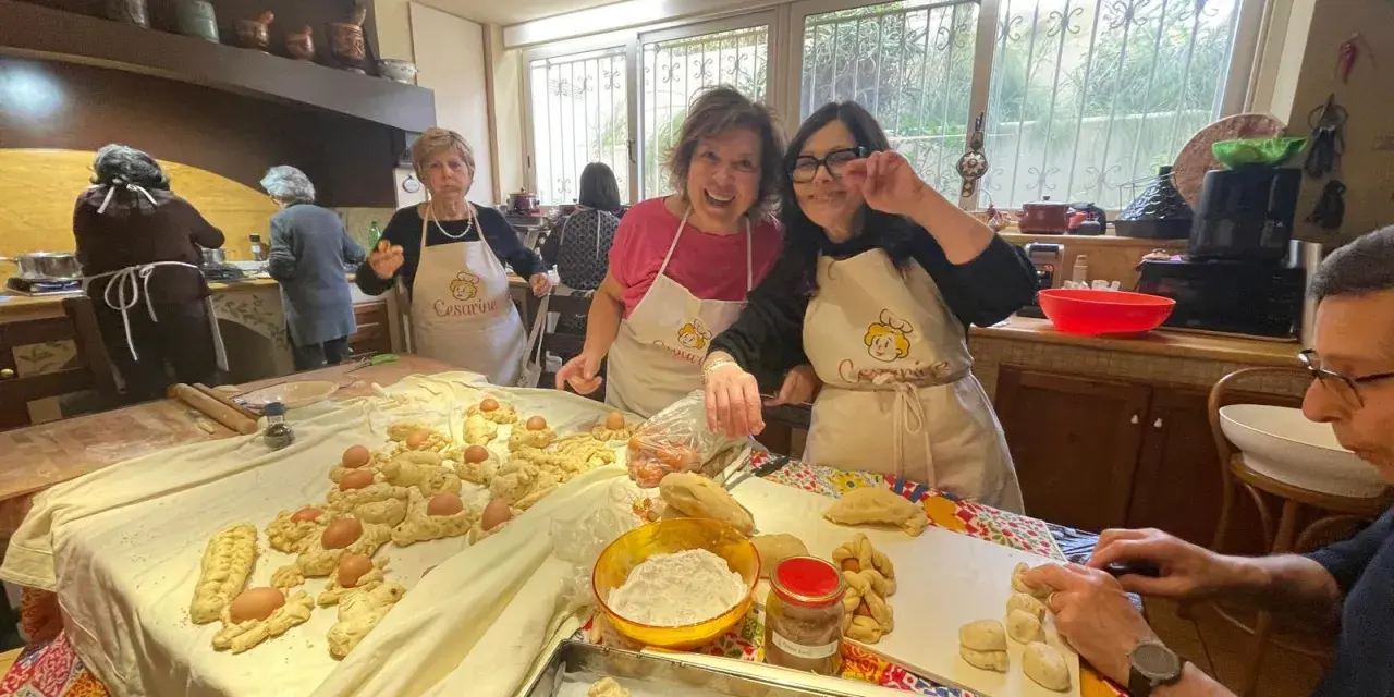 Donne sorridenti preparano impasti per piatti tipici di Perugia, con uova e pane intrecciato.