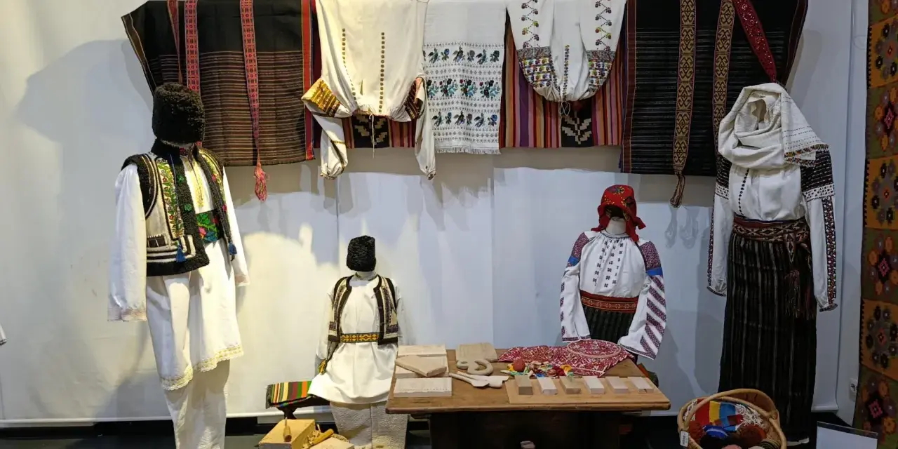 A Bucarest a dicembre, un'esposizione di abiti tradizionali rumeni, con manichini che indossano ricchi ricami e tessuti colorati.